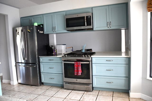 kitchen with blue cabinetry, stainless steel appliances, and light tile patterned floors