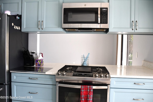 kitchen with light stone counters and appliances with stainless steel finishes