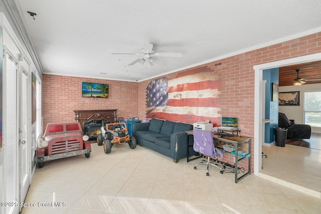 living room featuring ceiling fan, brick wall, a textured ceiling, and light tile patterned floors