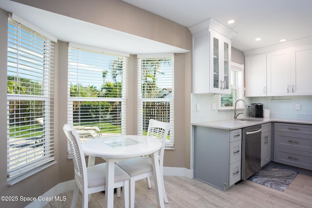 kitchen featuring white cabinetry, stainless steel dishwasher, gray cabinets, and backsplash