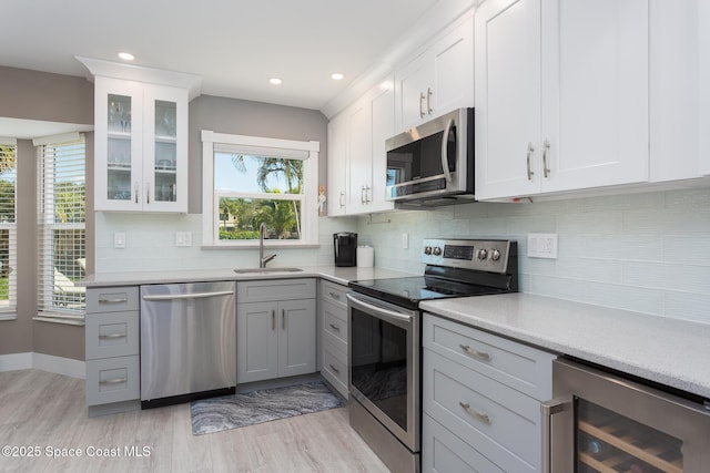 kitchen featuring white cabinetry, appliances with stainless steel finishes, sink, and beverage cooler