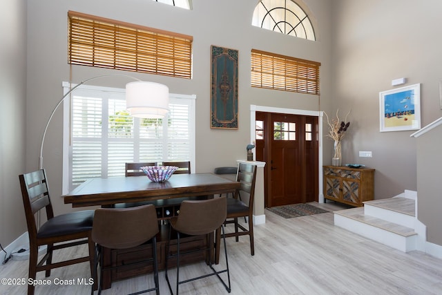 dining area featuring a high ceiling and light hardwood / wood-style floors