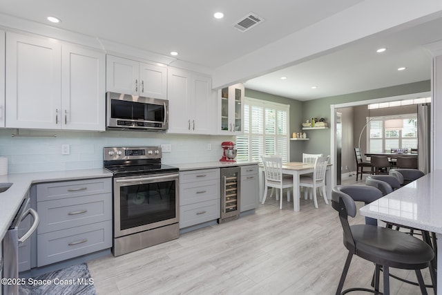 kitchen featuring wine cooler, a healthy amount of sunlight, stainless steel appliances, and white cabinets