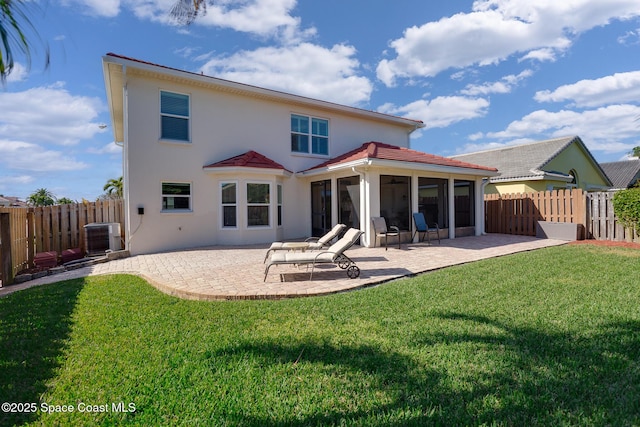 rear view of house with cooling unit, a sunroom, a yard, and a patio