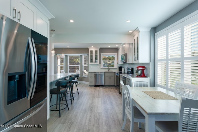 kitchen featuring white cabinetry, pendant lighting, stainless steel appliances, and decorative backsplash