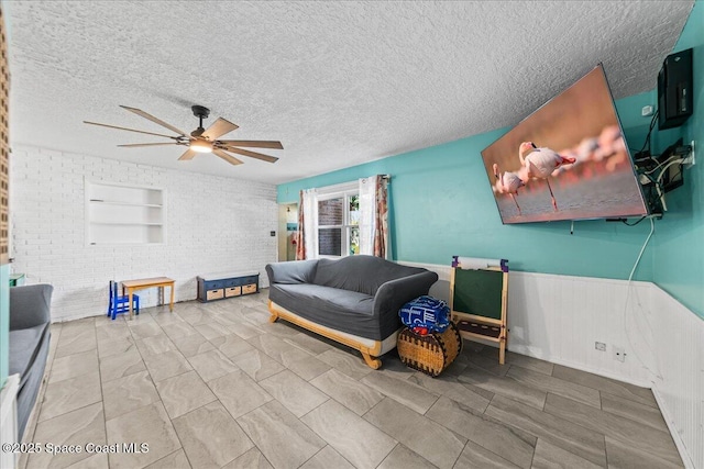 interior space featuring ceiling fan, brick wall, and a textured ceiling