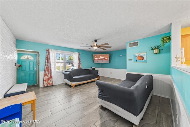 living room featuring ceiling fan and a textured ceiling