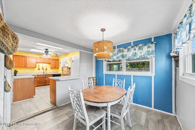 dining space with ceiling fan, sink, and a textured ceiling