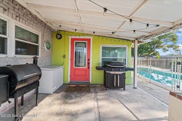 view of exterior entry with a fenced in pool and a patio area