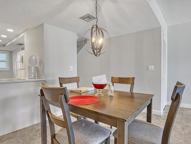 dining area featuring light tile patterned floors, a textured ceiling, and a notable chandelier