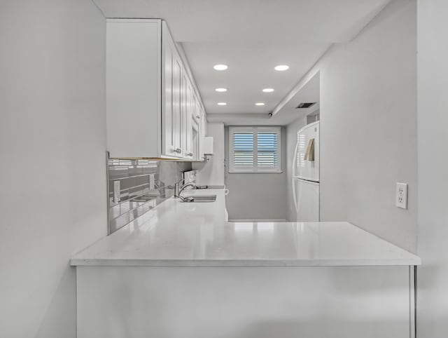 kitchen with sink, tasteful backsplash, white fridge, light stone countertops, and white cabinets