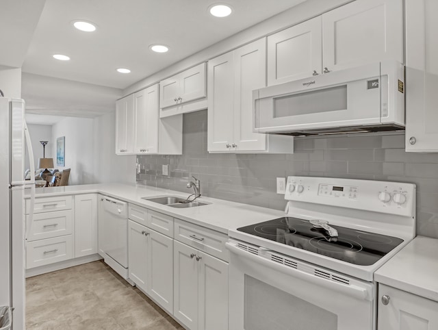 kitchen featuring tasteful backsplash, white cabinetry, sink, kitchen peninsula, and white appliances