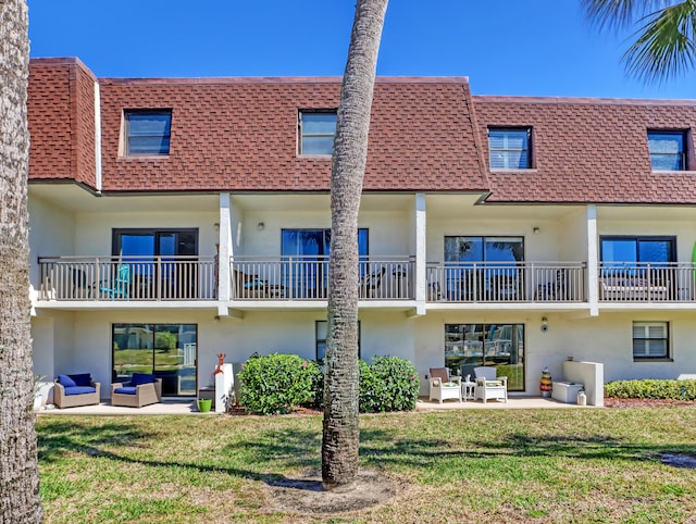 rear view of property featuring an outdoor hangout area, a lawn, and a patio