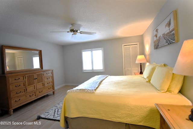 bedroom with ceiling fan, wood-type flooring, a closet, and a textured ceiling