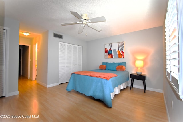 bedroom with ceiling fan, hardwood / wood-style floors, a closet, and a textured ceiling