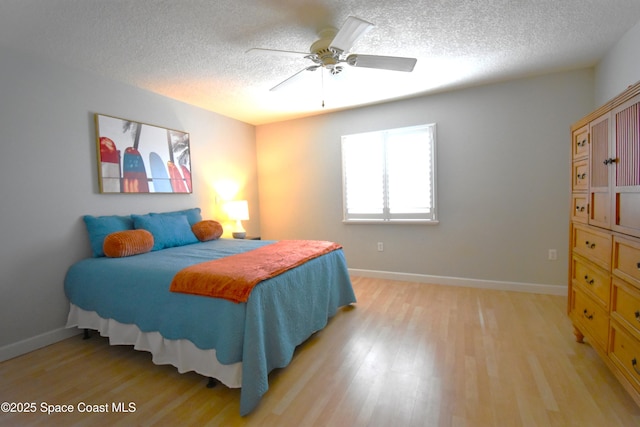 bedroom featuring ceiling fan, light hardwood / wood-style flooring, and a textured ceiling