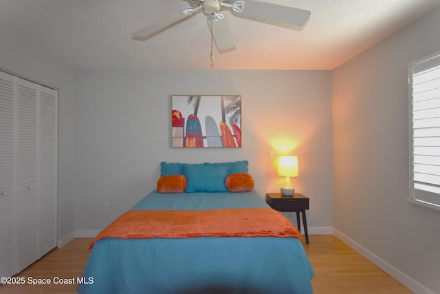 bedroom featuring ceiling fan, light hardwood / wood-style flooring, a closet, and a textured ceiling