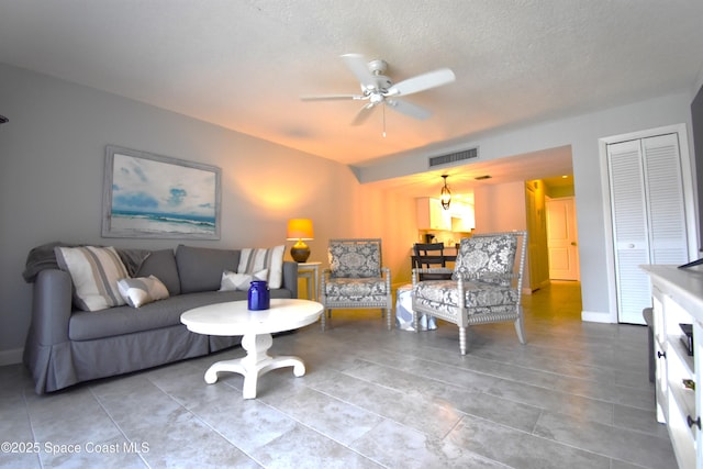 living room with ceiling fan, tile patterned floors, and a textured ceiling