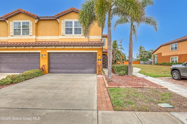 townhome / multi-family property featuring stucco siding, a garage, driveway, and a tiled roof