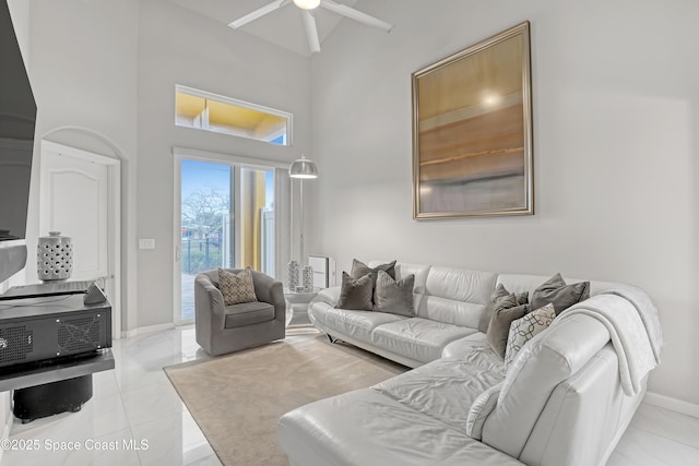 living room with baseboards, ceiling fan, and a towering ceiling