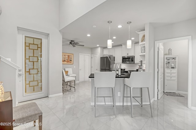 kitchen with a breakfast bar, stainless steel appliances, a peninsula, white cabinets, and ceiling fan