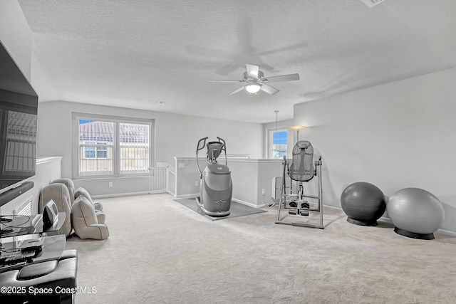 workout room featuring carpet floors, a textured ceiling, a healthy amount of sunlight, and a ceiling fan