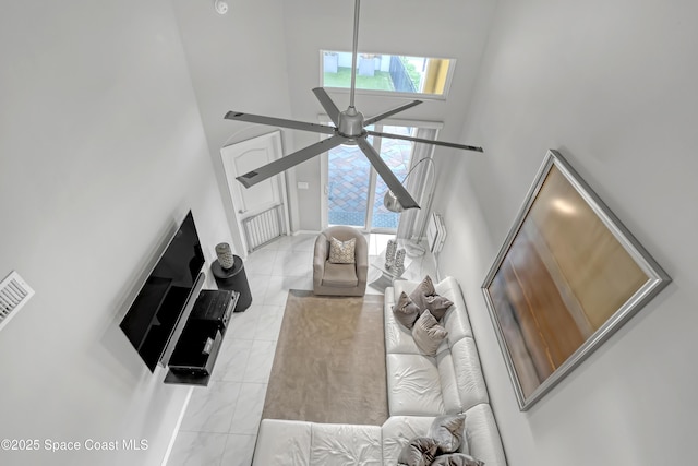 living room with ceiling fan, a towering ceiling, and light tile patterned floors