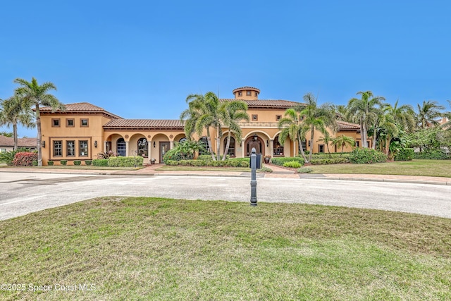 view of front of house featuring a tile roof, a front yard, and stucco siding