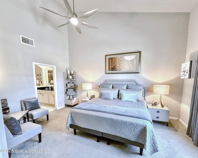 bedroom with baseboards, visible vents, a high ceiling, light carpet, and connected bathroom