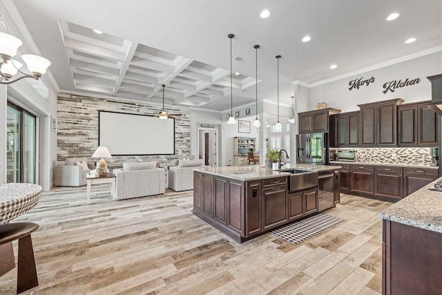 kitchen with pendant lighting, sink, a large island, light stone countertops, and dark brown cabinets