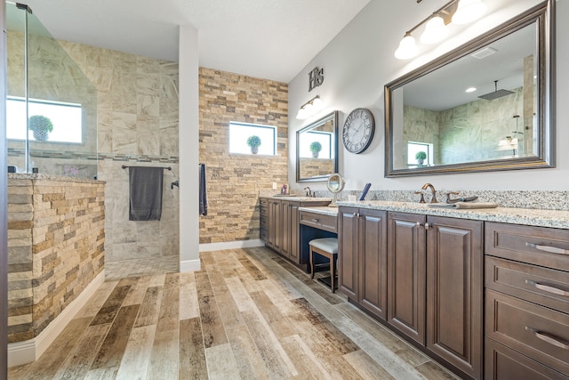 bathroom with hardwood / wood-style flooring, vanity, a wealth of natural light, and a tile shower