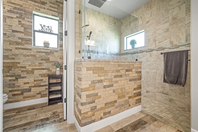 bathroom featuring hardwood / wood-style floors, toilet, and tiled shower