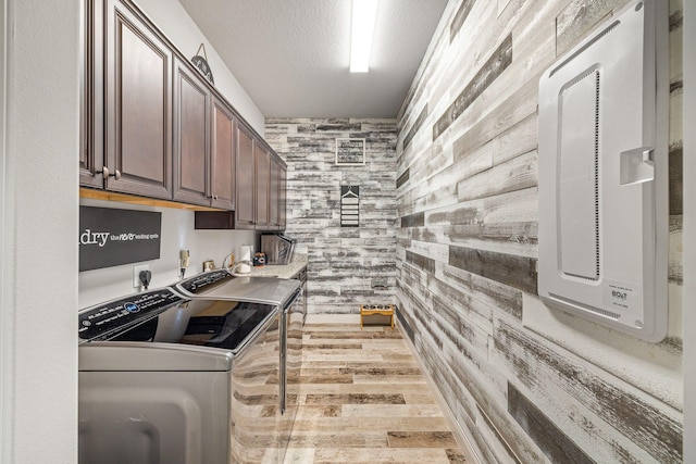 kitchen with hardwood / wood-style flooring, a textured ceiling, washing machine and clothes dryer, and dark brown cabinetry