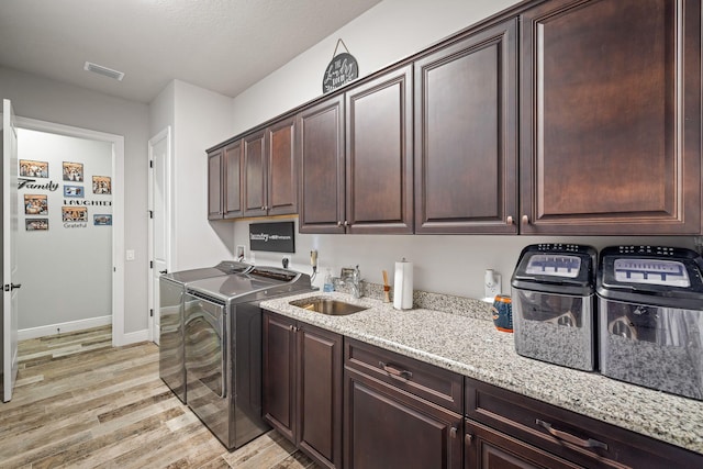 laundry area with cabinets, sink, washing machine and dryer, and light hardwood / wood-style flooring