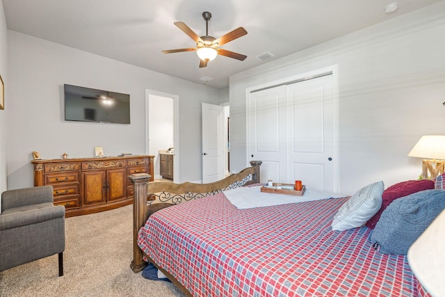 bedroom featuring ensuite bathroom, light colored carpet, ceiling fan, and a closet