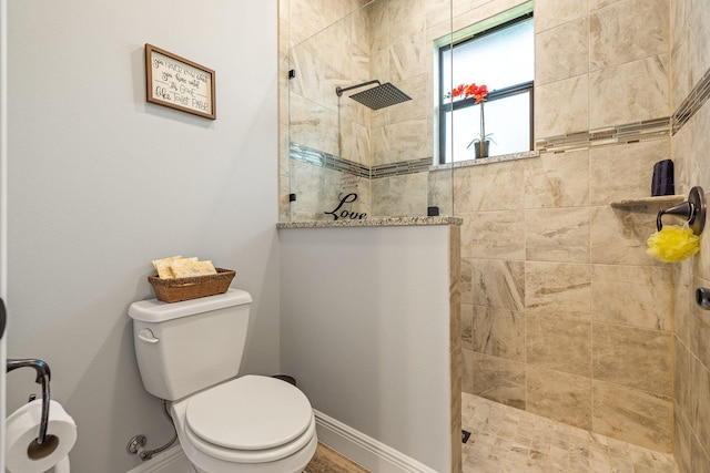 bathroom with a tile shower and toilet