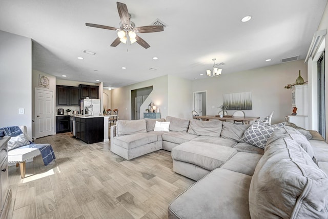 living room featuring ceiling fan with notable chandelier and light hardwood / wood-style floors