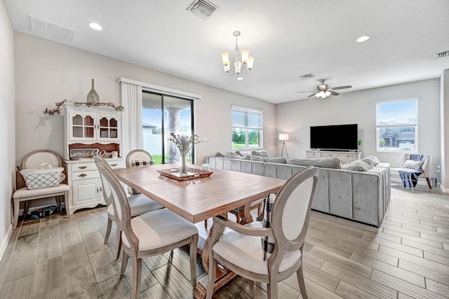 dining space with a healthy amount of sunlight and ceiling fan with notable chandelier