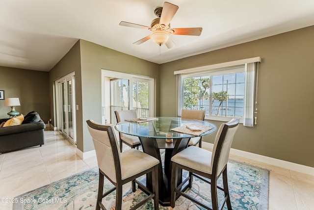 dining room featuring a water view, ceiling fan, and light tile patterned floors