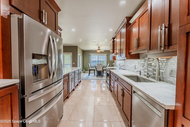 kitchen featuring sink, light tile patterned floors, appliances with stainless steel finishes, light stone counters, and decorative backsplash