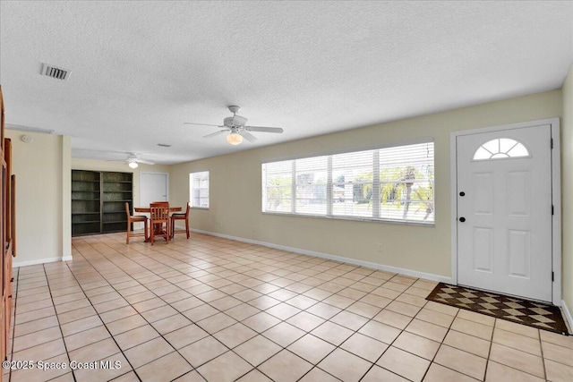 tiled entrance foyer with ceiling fan and a textured ceiling