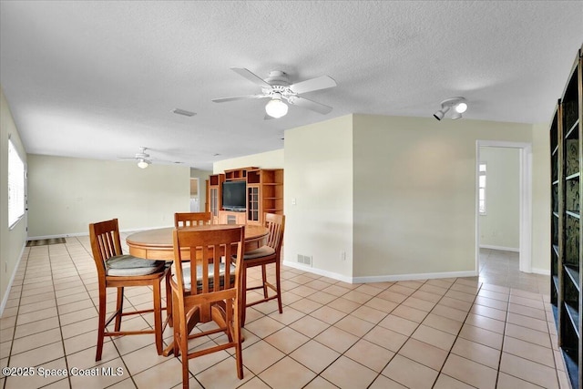 dining room featuring light tile patterned floors, a textured ceiling, a healthy amount of sunlight, and ceiling fan