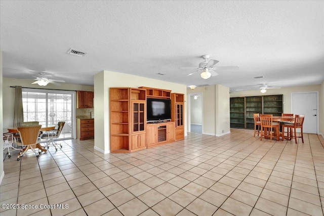 living room featuring light tile patterned floors, a textured ceiling, and ceiling fan