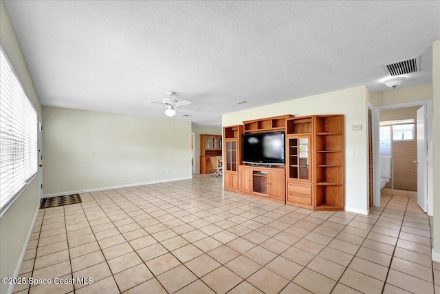 unfurnished living room with light tile patterned flooring, ceiling fan, and a textured ceiling