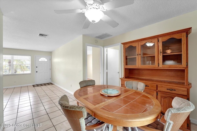 tiled dining room with ceiling fan and a textured ceiling