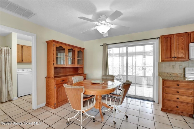 tiled dining room featuring ceiling fan, washer / dryer, and a textured ceiling