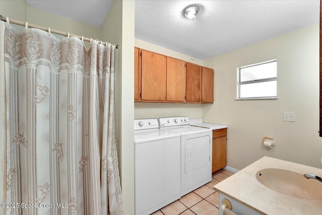 laundry area with sink, light tile patterned floors, washer and dryer, and a textured ceiling