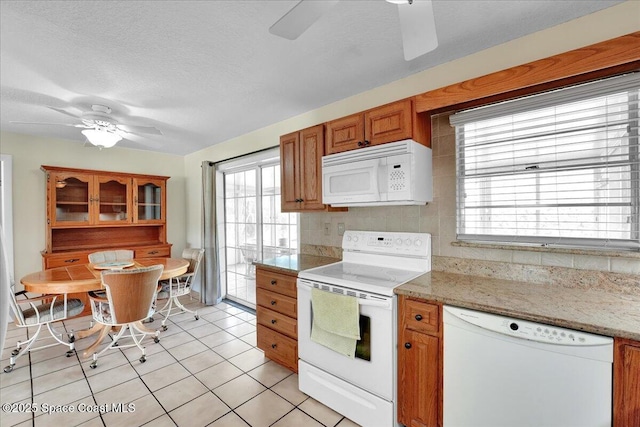 kitchen featuring white appliances, ceiling fan, backsplash, light stone counters, and light tile patterned flooring