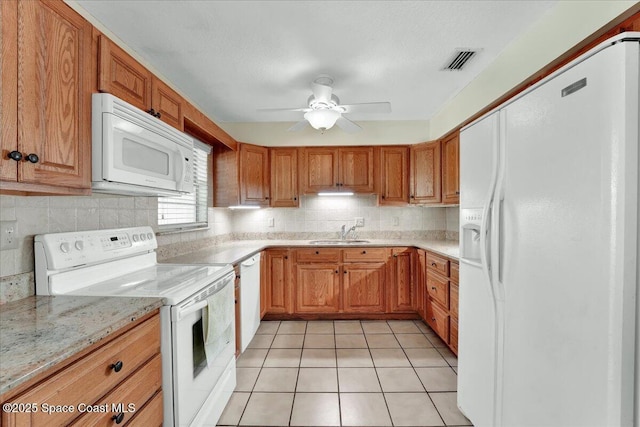 kitchen with sink, white appliances, light stone counters, tasteful backsplash, and light tile patterned flooring