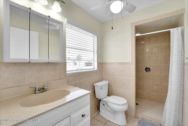 bathroom with toilet, tile walls, vanity, curtained shower, and tile patterned flooring